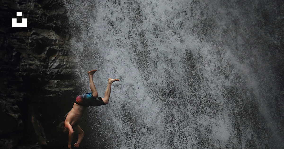 Two people jumping off a waterfall into a body of water photo – Free ...