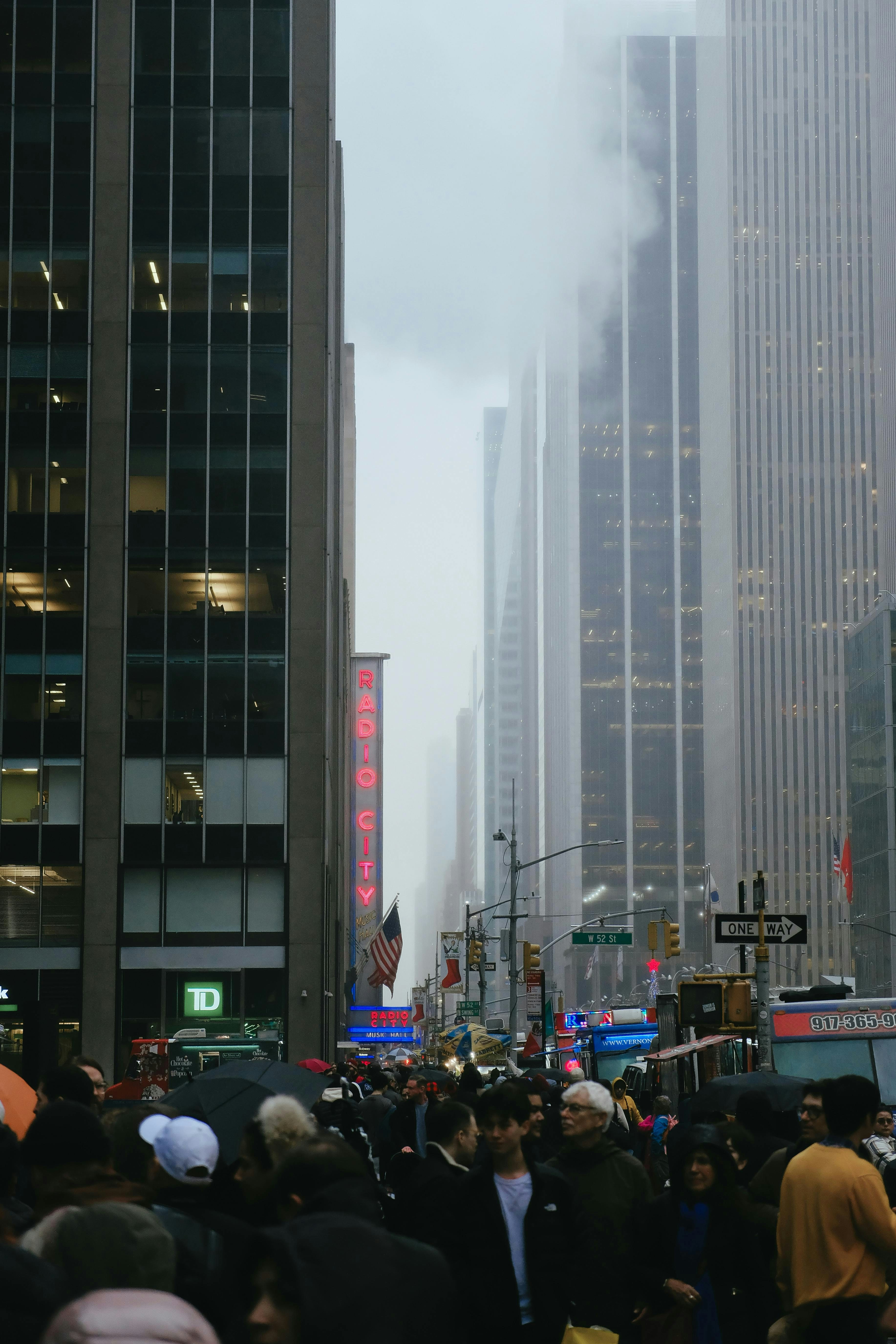 A crowd of people standing on a street next to tall buildings