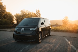 A black van driving down a road next to a forest