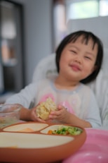 A little girl sitting at a table eating food