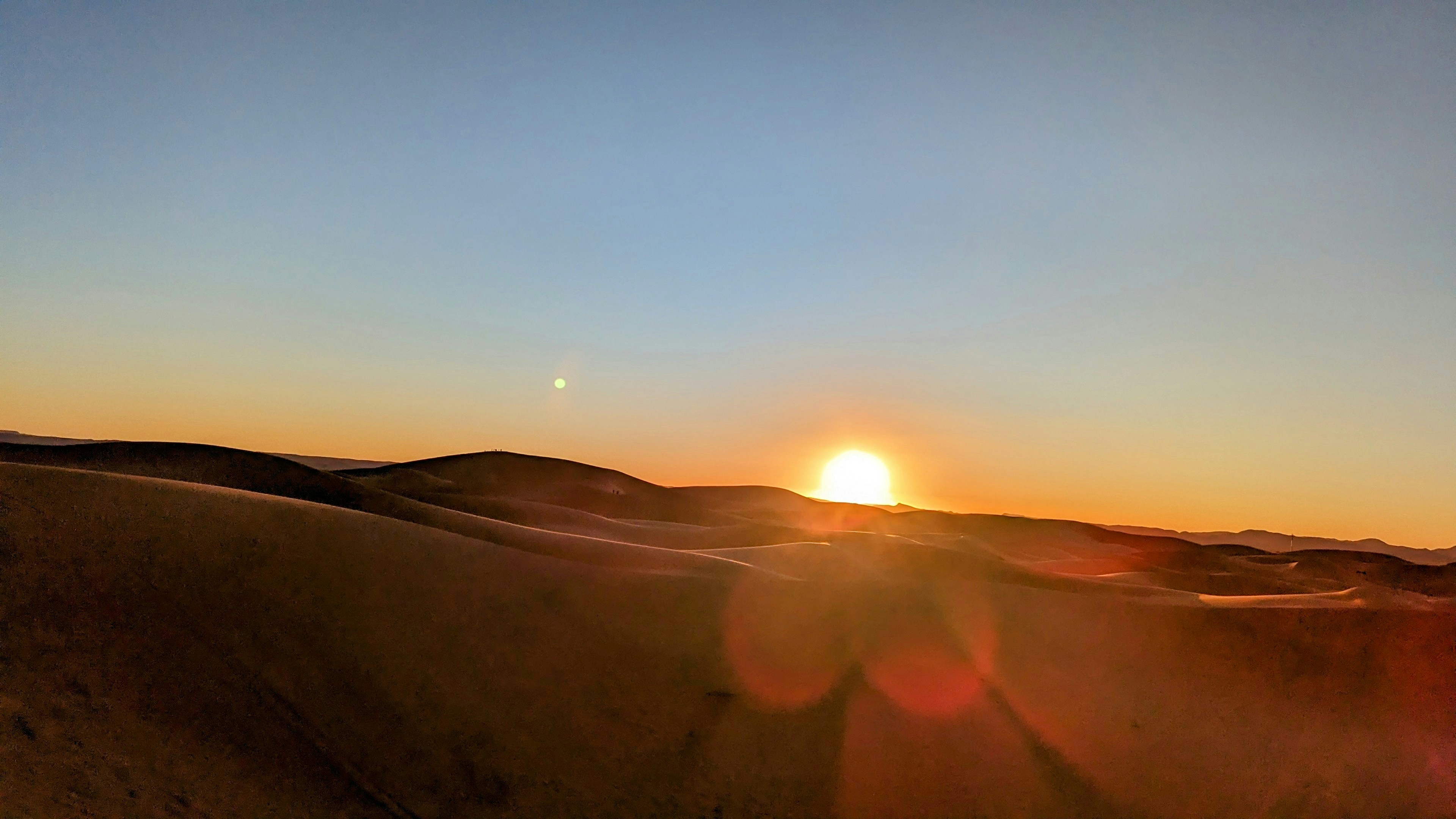 Ancient desert dunes at sunset casting long dramatic shadows across vast golden sand landscape