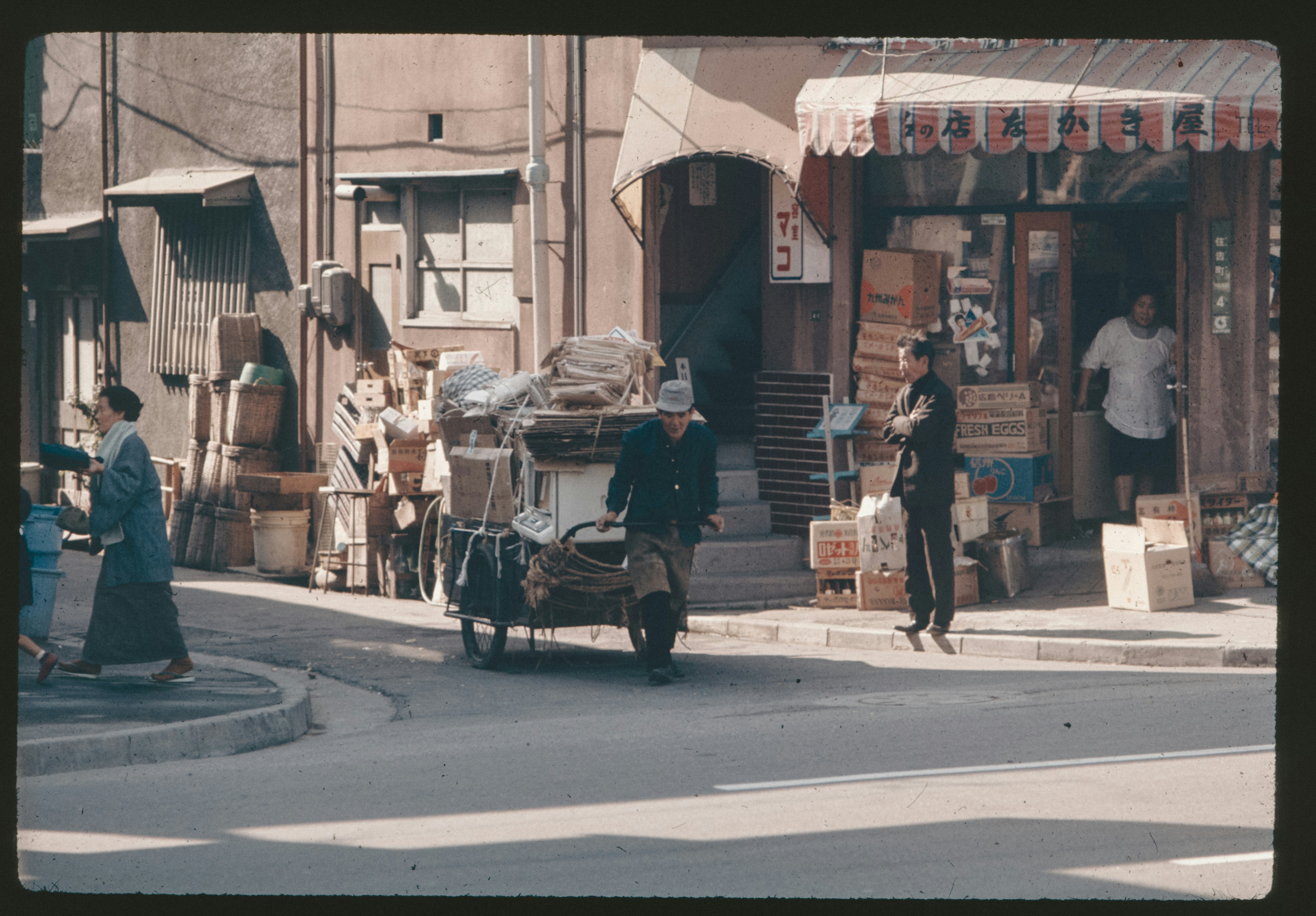 An old photo of a man pushing a cart down a street
