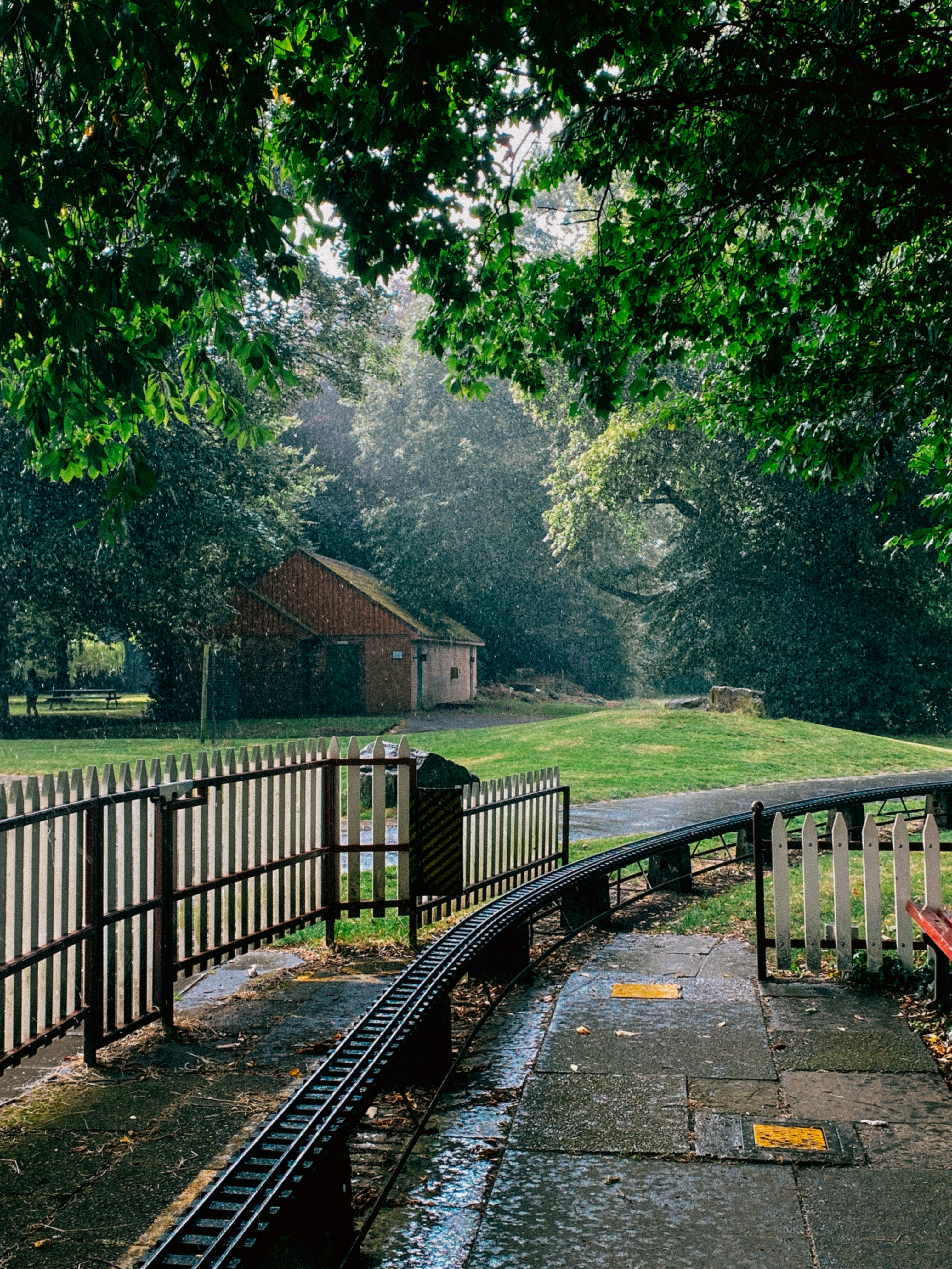 A red bench sitting on top of a sidewalk next to a fence