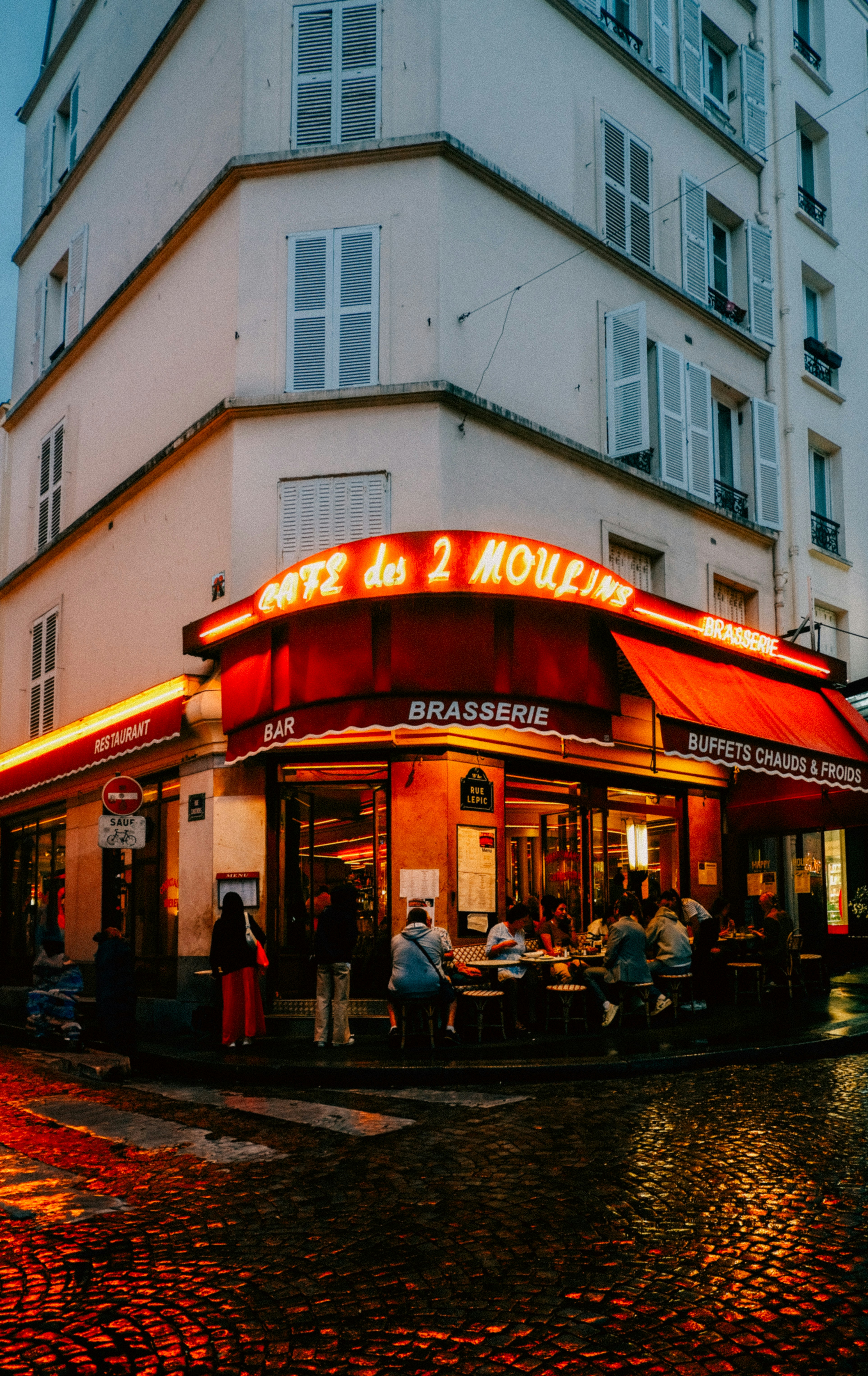 A restaurant with a red awning on a rainy day
