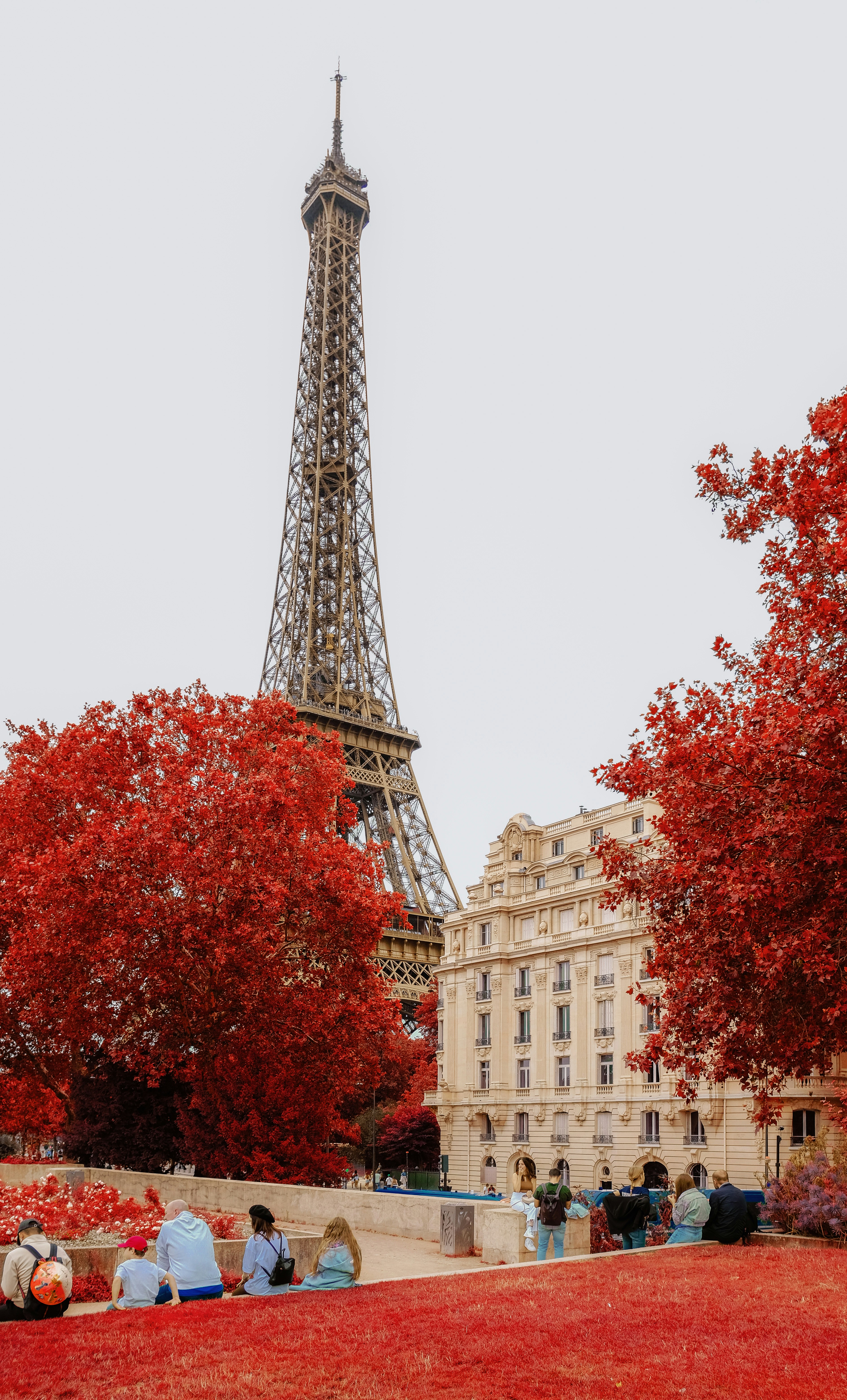 A group of people sitting on a bench in front of the eiffel tower