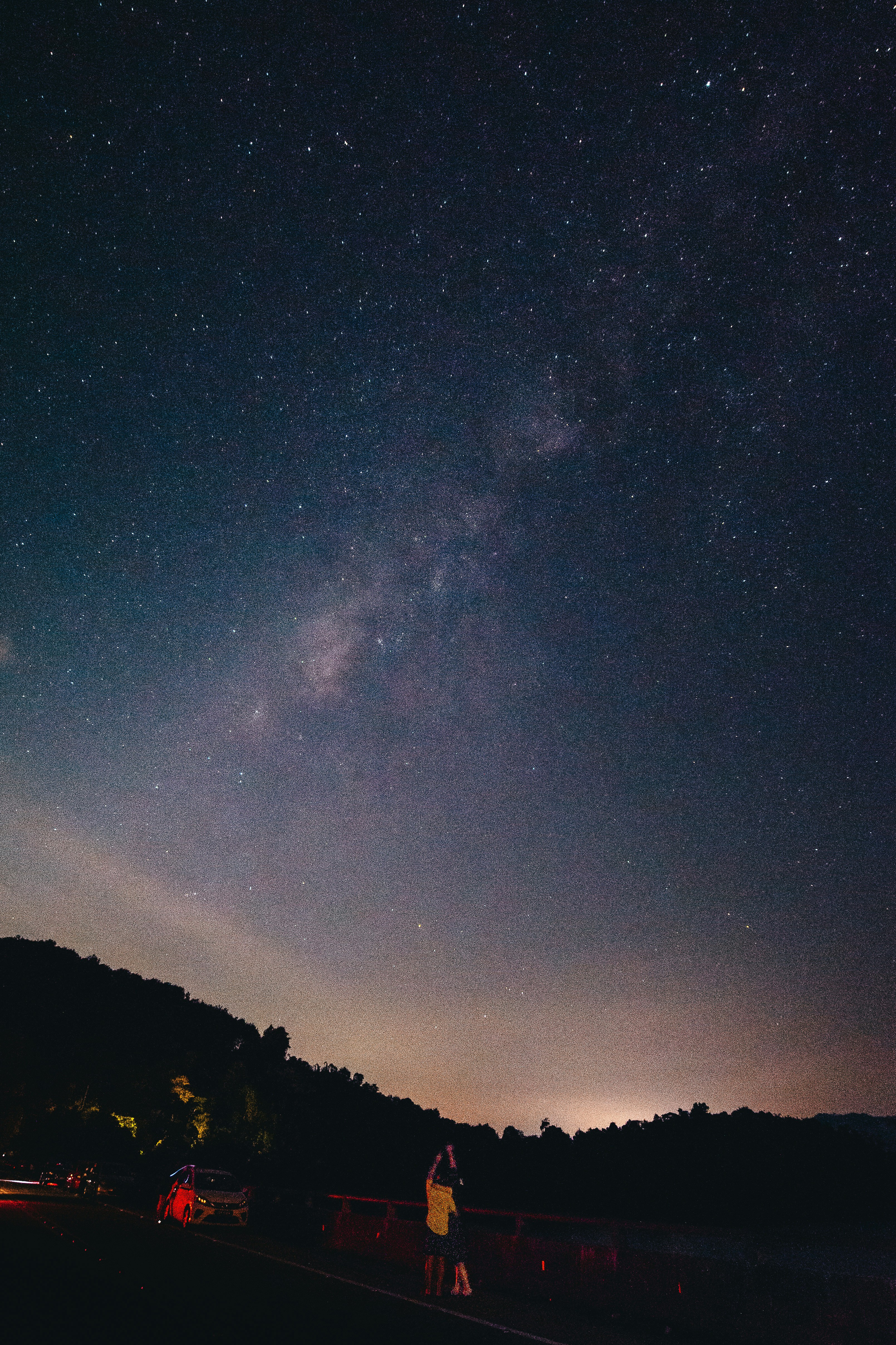 A person standing on the side of a road under a night sky filled with stars