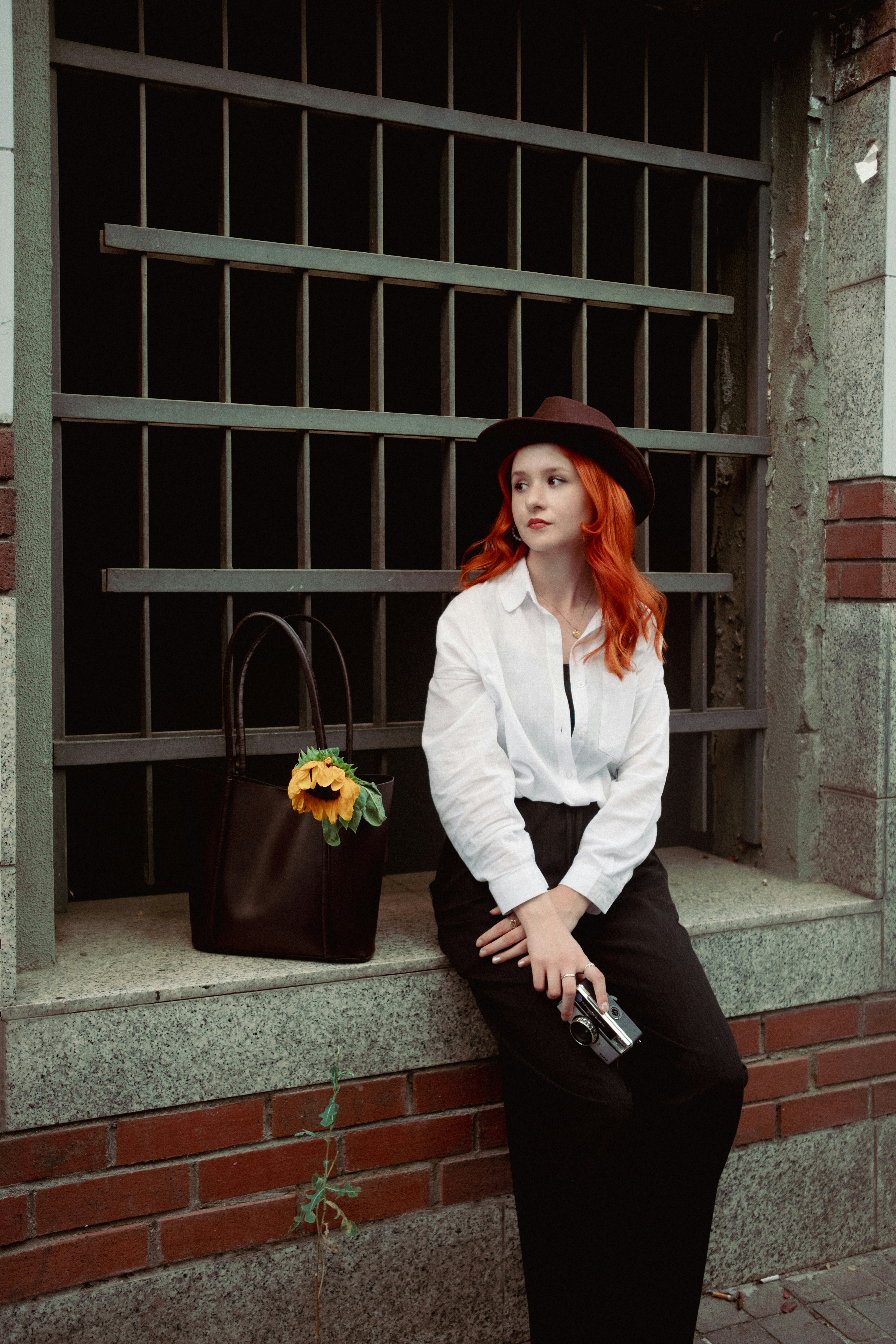 A woman with red hair sitting on a window sill