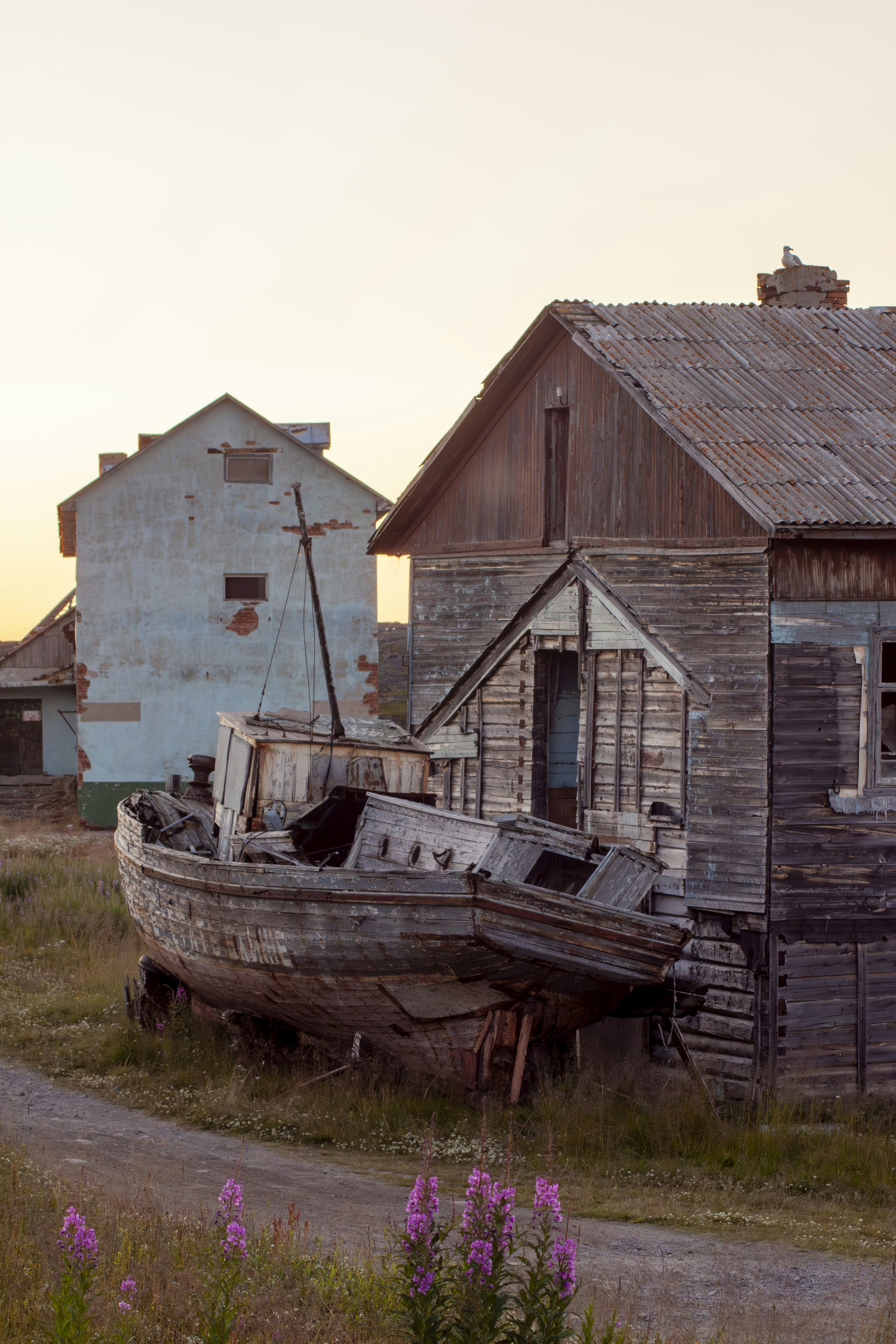 An old boat sitting in a field next to a building photo – Free Russia ...