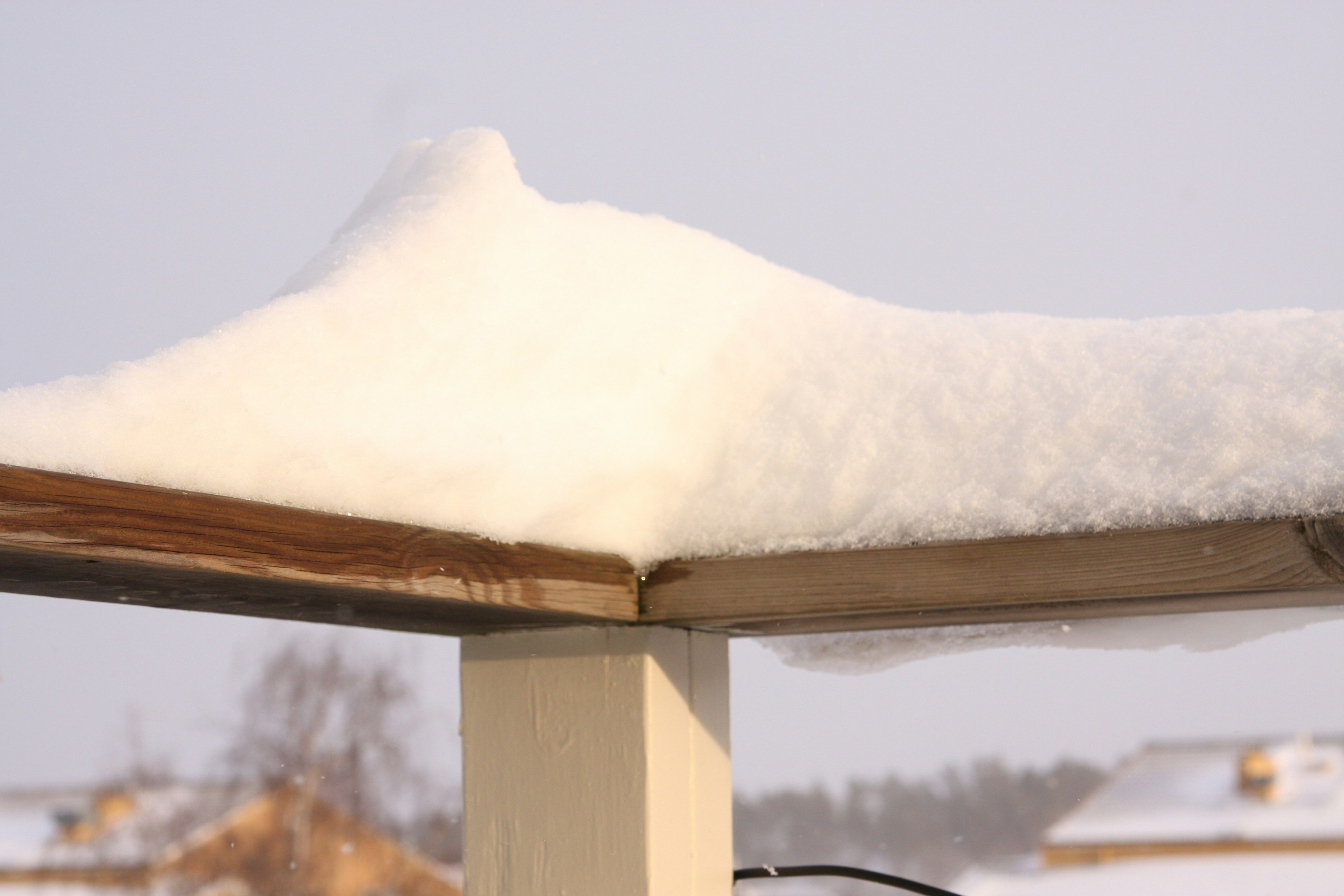 A snow covered roof with a bird sitting on top of it