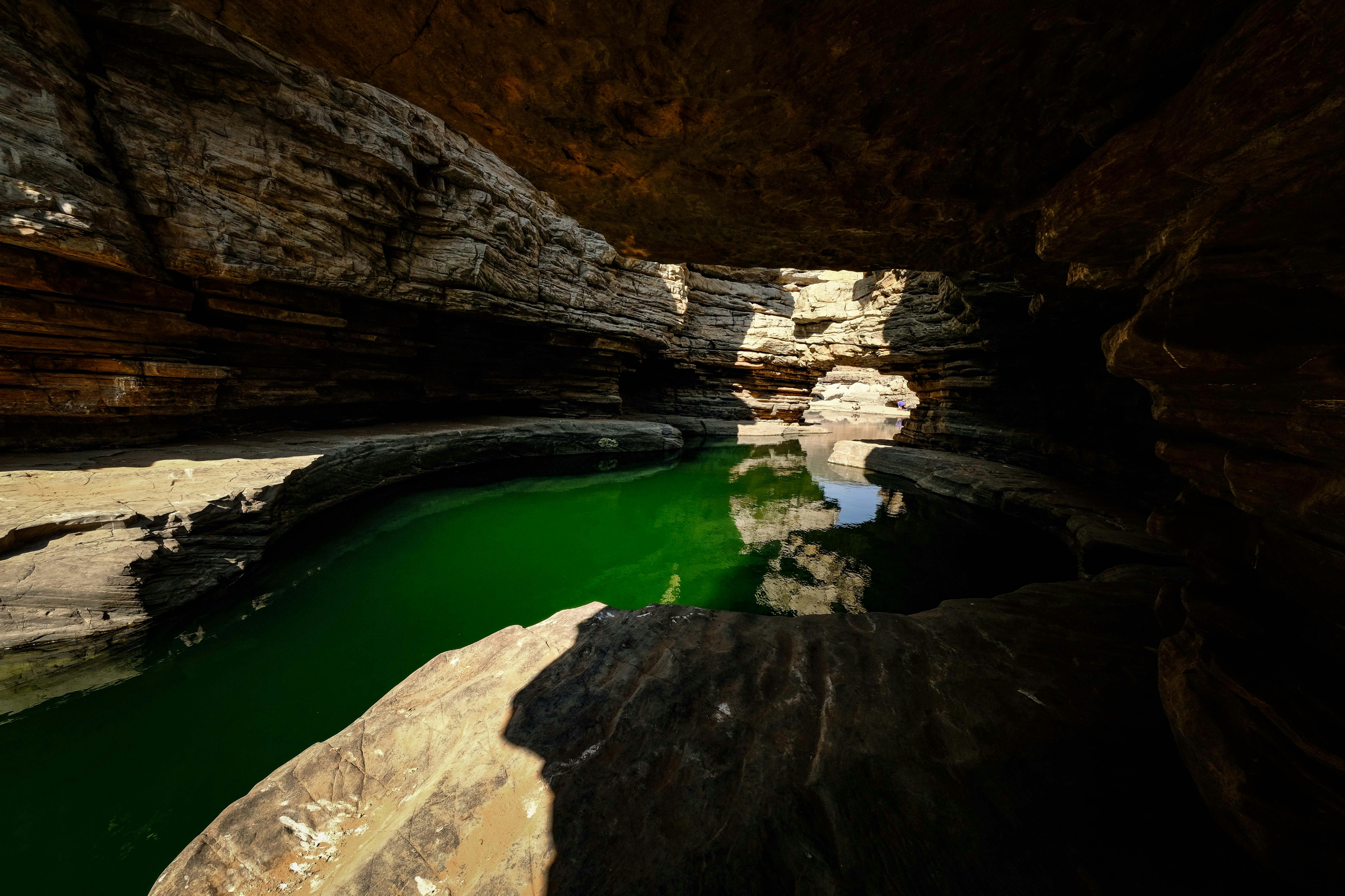 A green pool of water in the middle of a cave