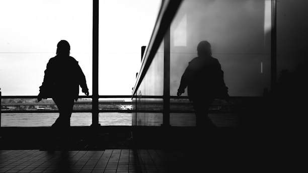 A couple of people that are standing in front of a window