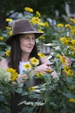 A woman in a hat standing in a field of flowers