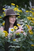 A woman in a hat standing in a field of flowers