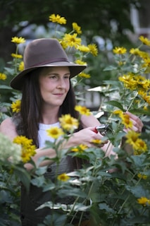 A woman in a hat standing in a field of flowers