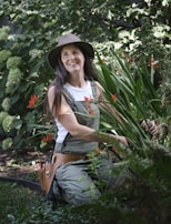 A woman sitting in a garden with a hat on
