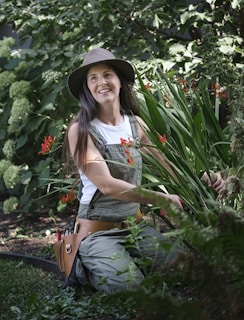 A woman sitting in a garden with a hat on