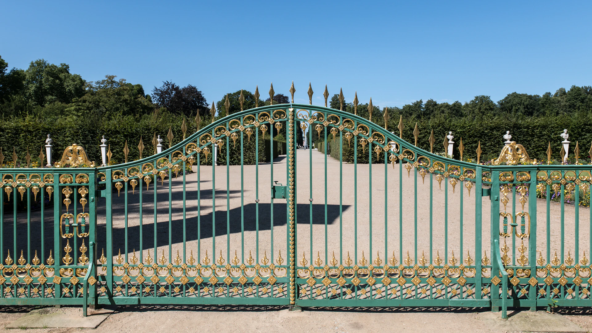 A large green gate with a walkway leading to it