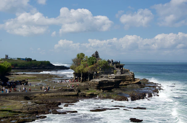 A group of people standing on top of a cliff next to the ocean