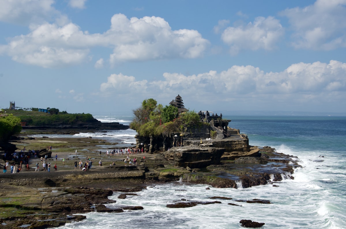 A group of people standing on top of a cliff next to the ocean