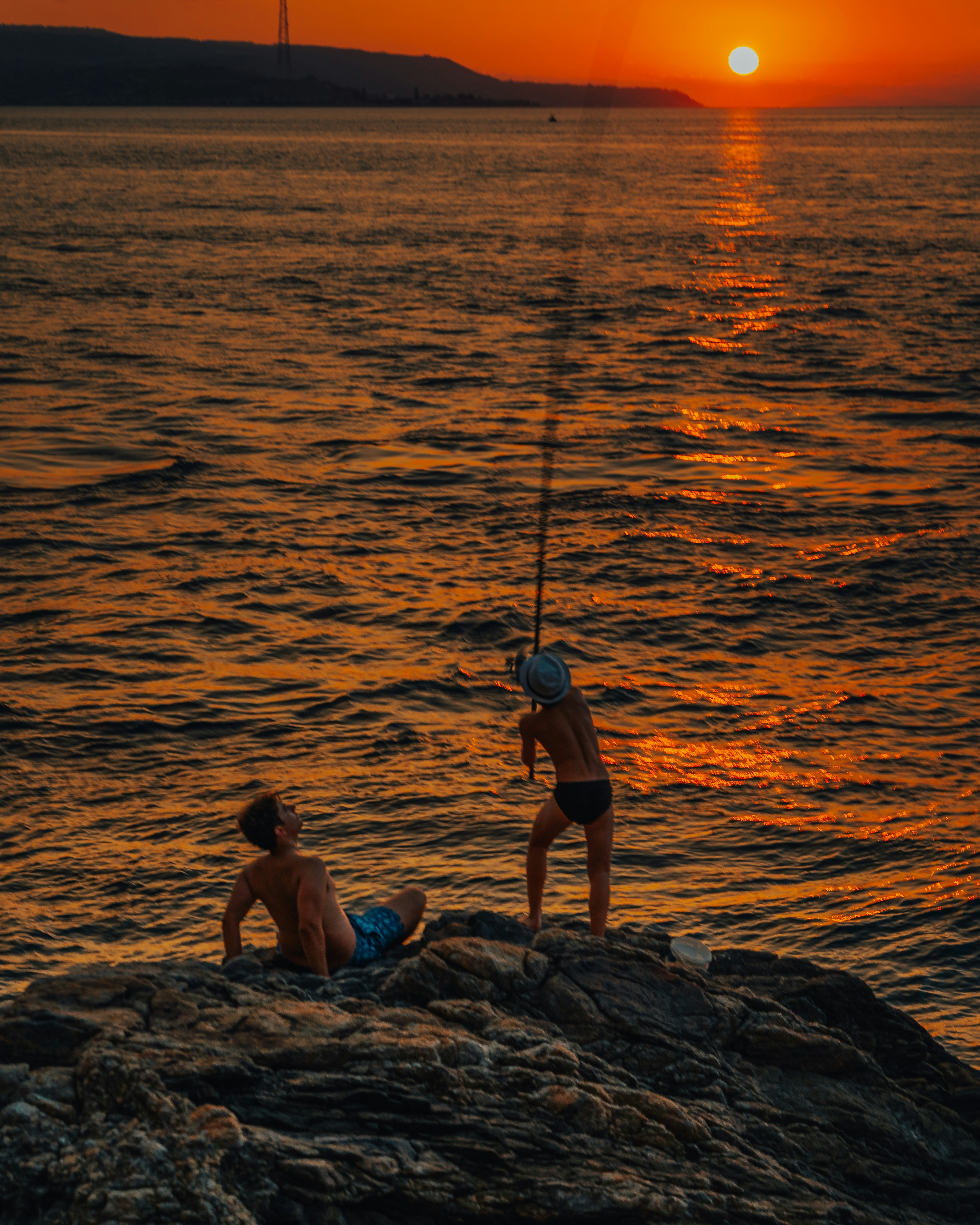A couple of people standing on top of a rock near the ocean