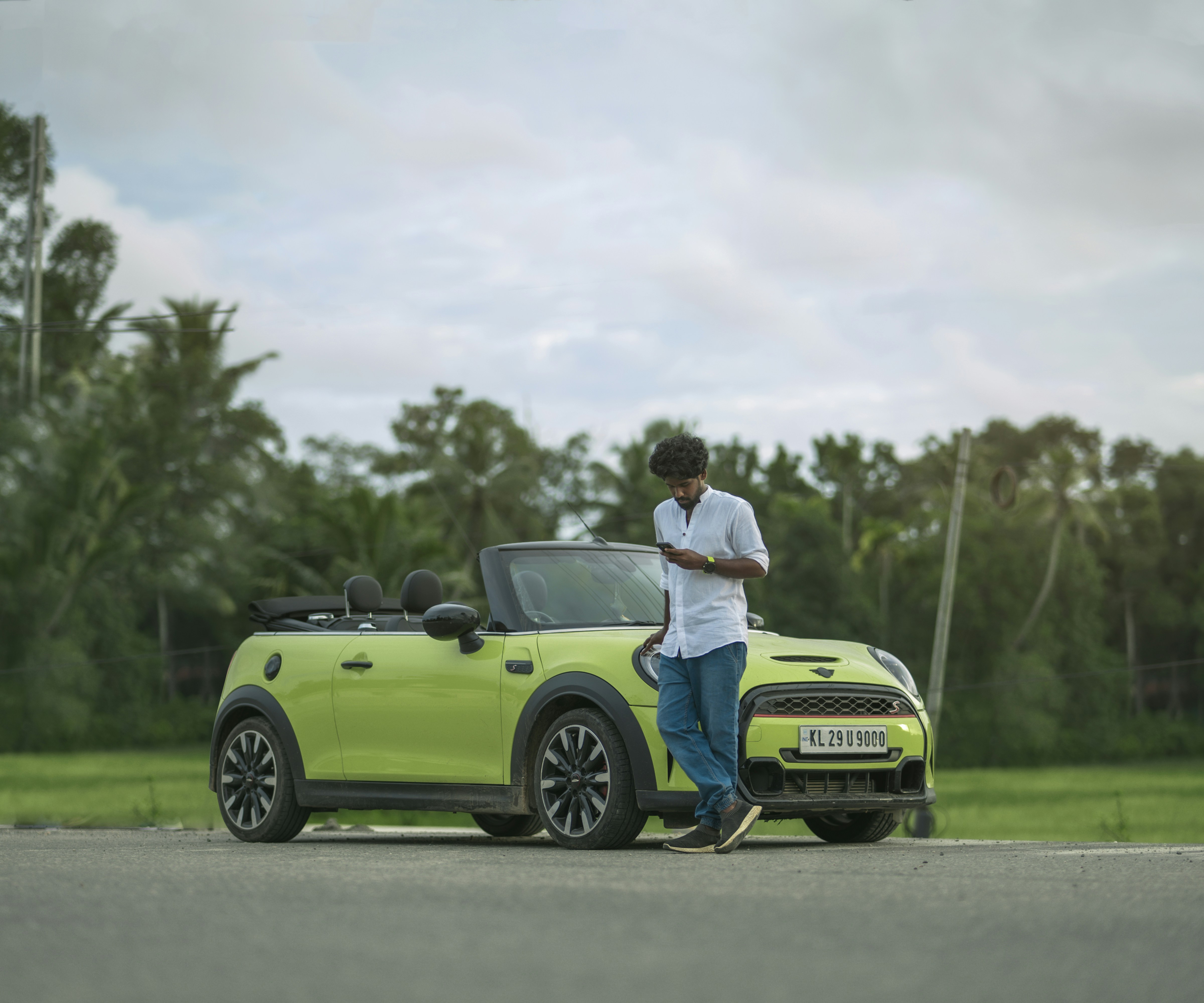 A man standing next to a green mini cooper