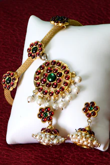 A white pillow with red and green beads on it