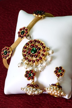 A white pillow with red and green beads on it