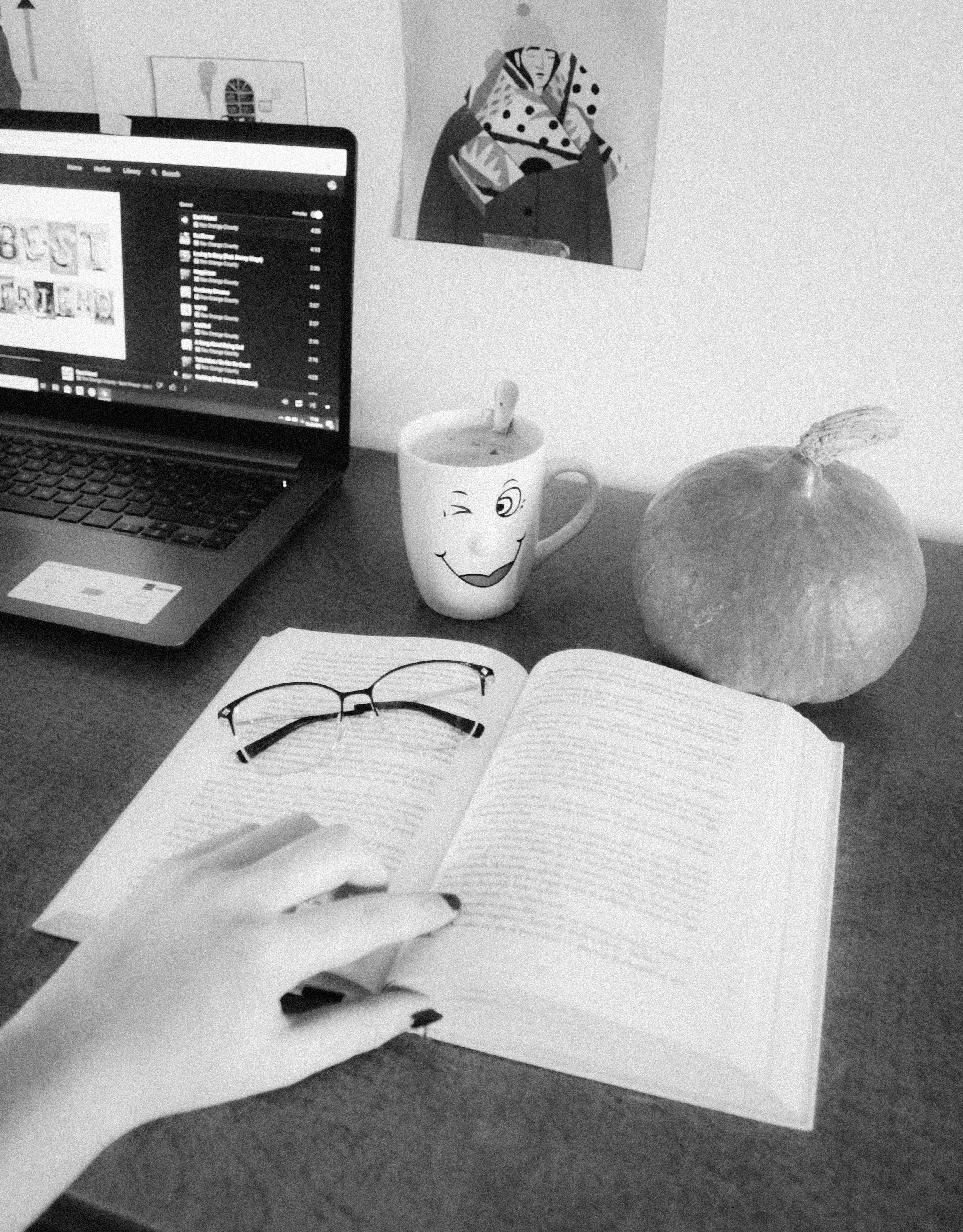 A person sitting at a desk with a laptop and a book