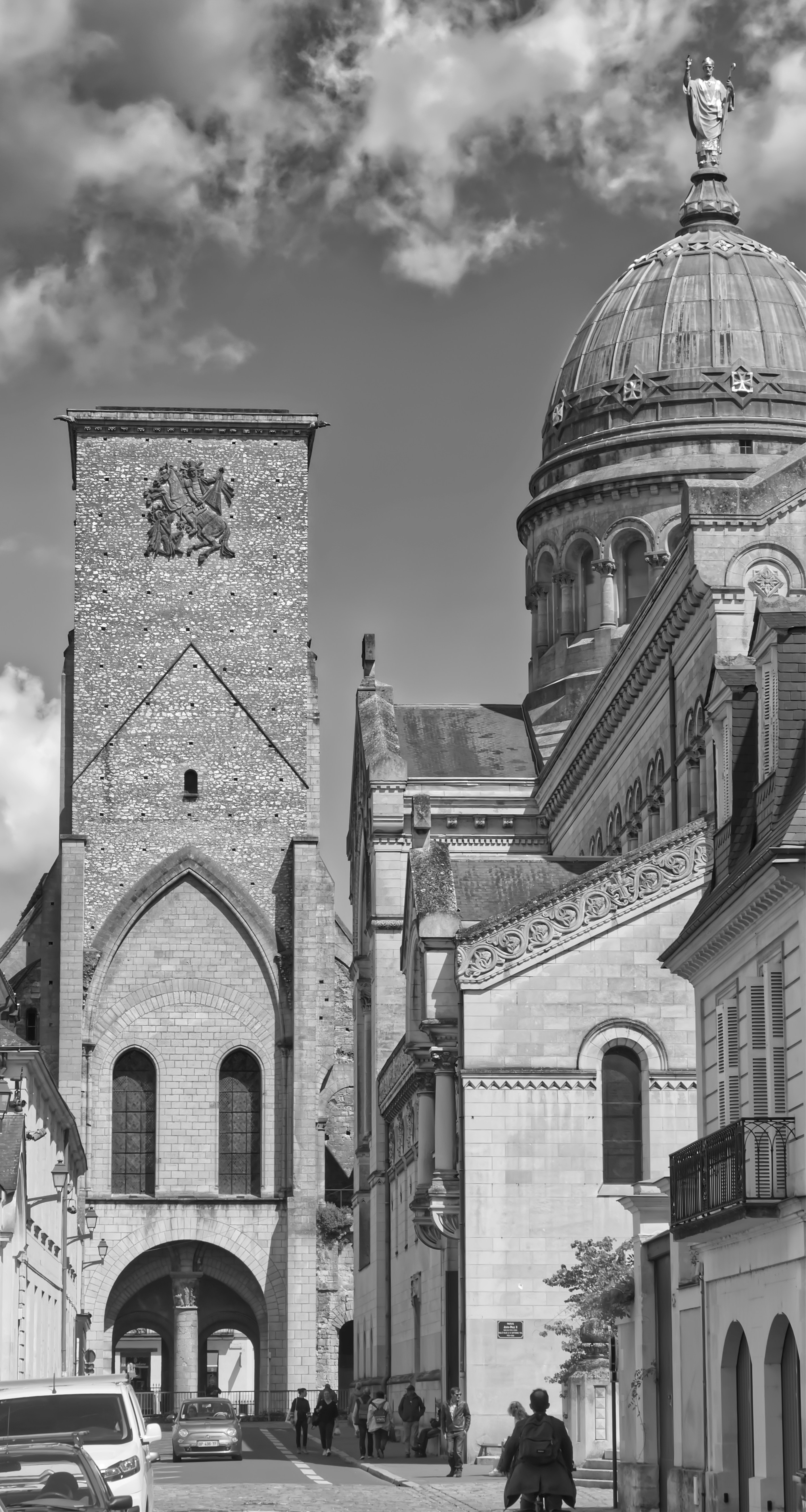 A black and white photo of a building with a car parked in front of it