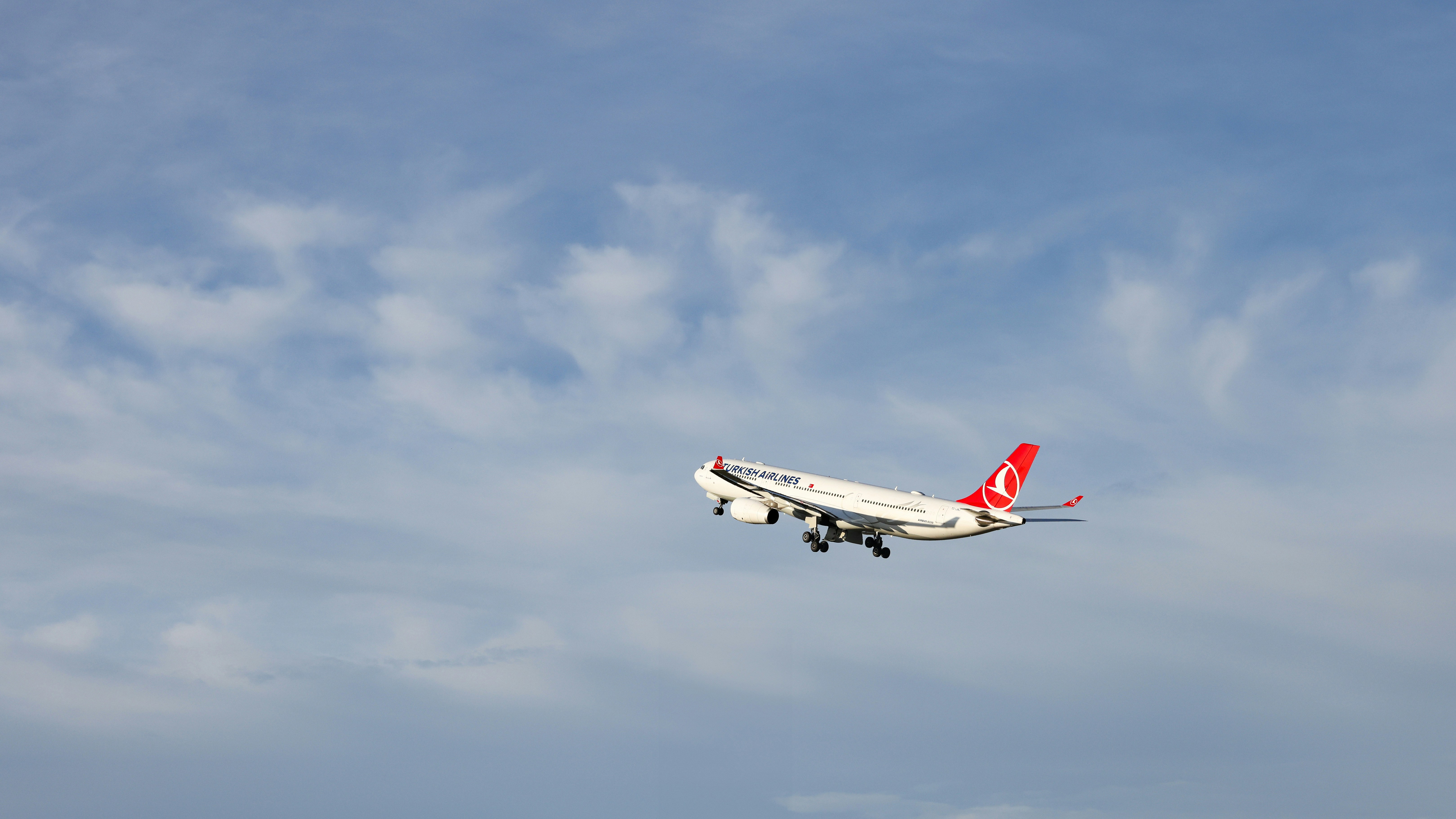 A large jetliner flying through a blue cloudy sky, A Turkish Airlines Airbus A330-300 climbing steadily into the sky.