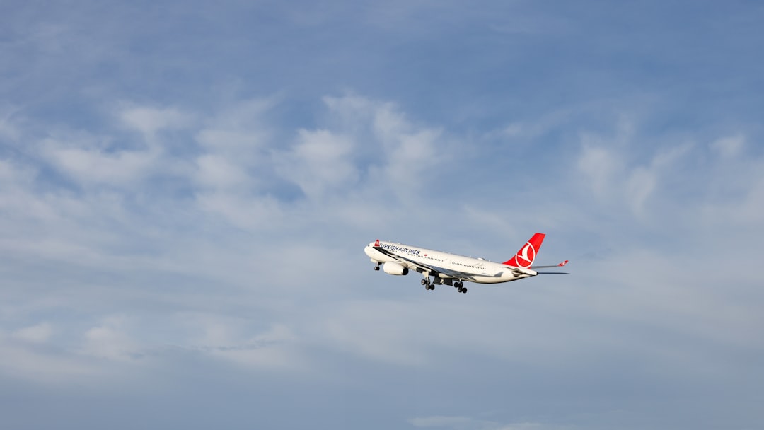 A large jetliner flying through a blue cloudy sky, A Turkish Airlines Airbus A330-300 climbing steadily into the sky.