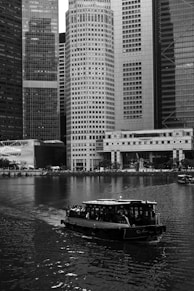A boat traveling down a river next to tall buildings