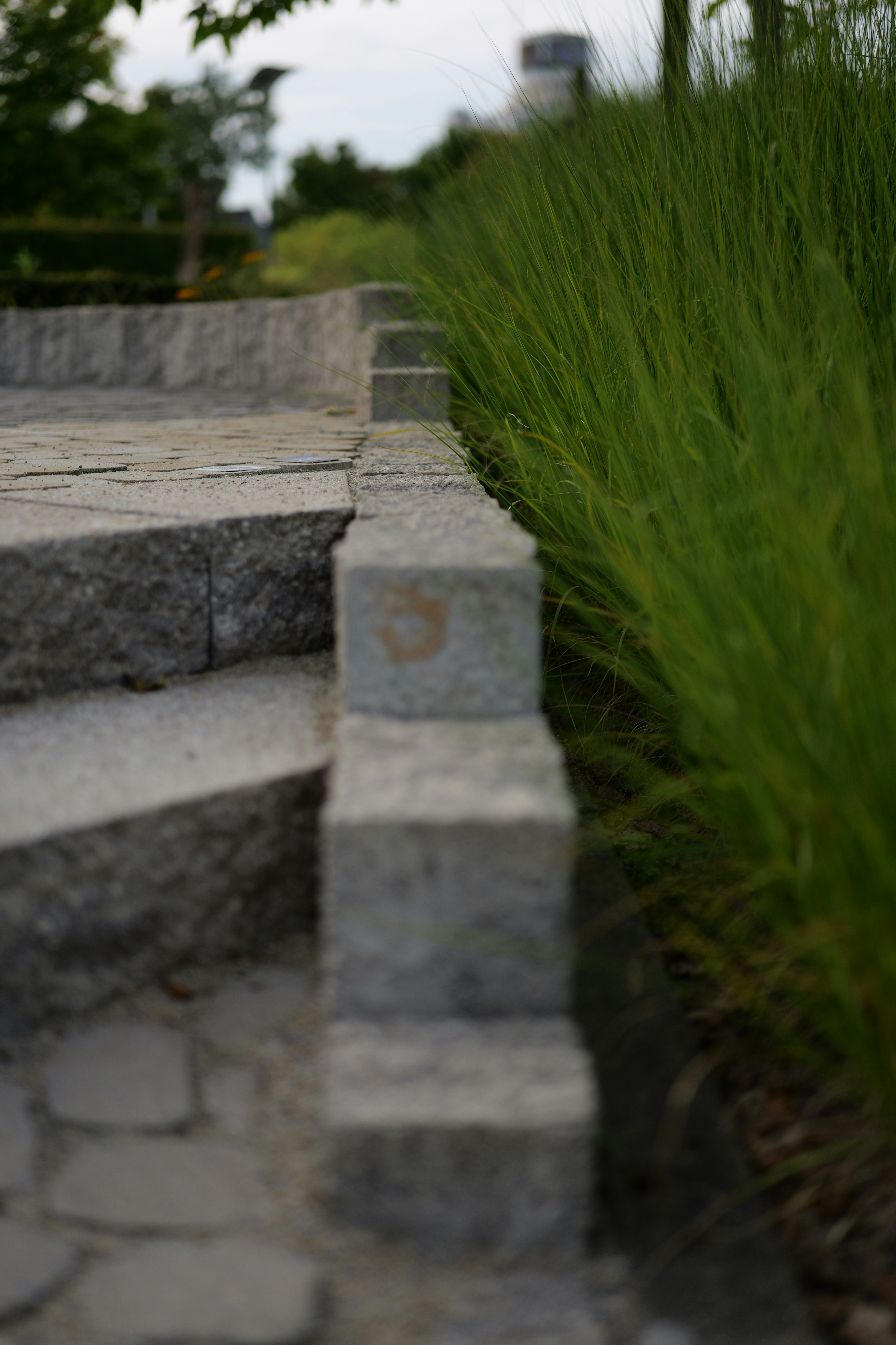 A stone bench sitting next to a lush green field