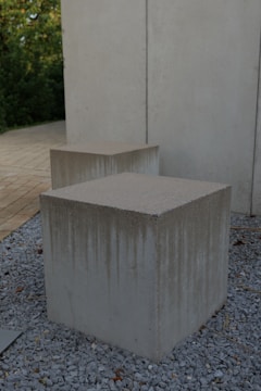 Two concrete boxes sitting on top of a gravel field