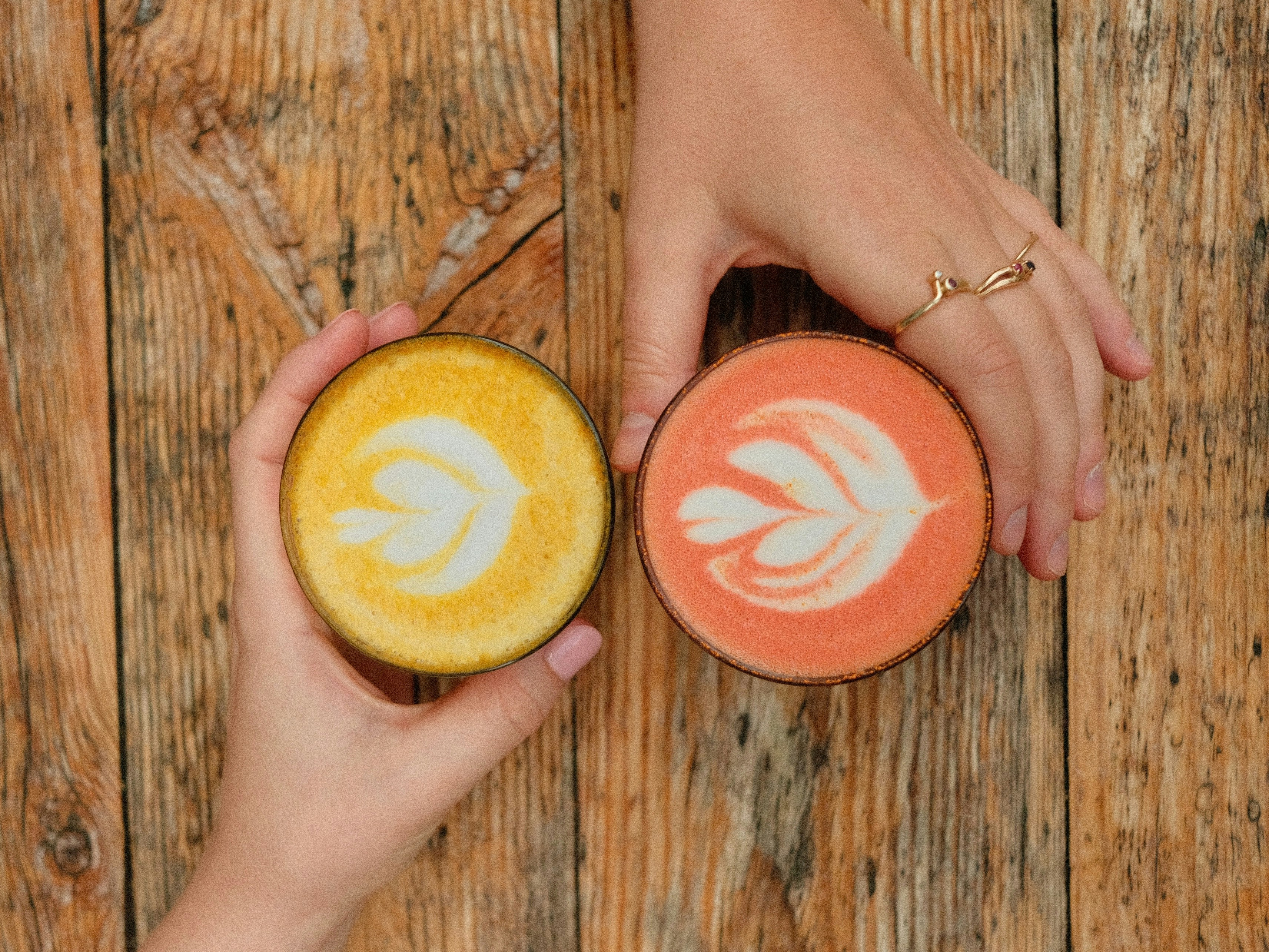 A person holding two frisbees on a wooden surface