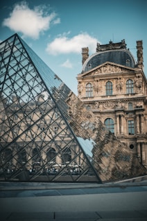 A large building with a glass pyramid in front of it