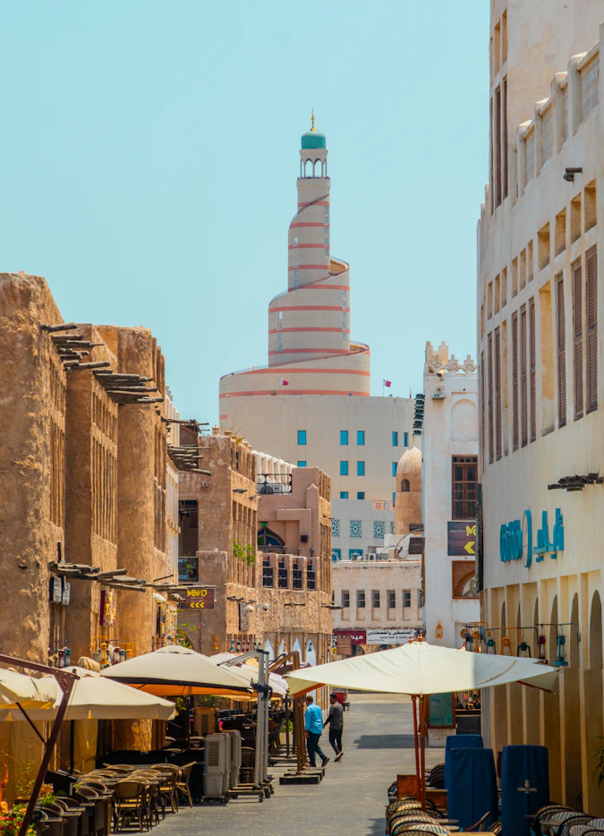 A narrow street with tables and umbrellas on both sides
