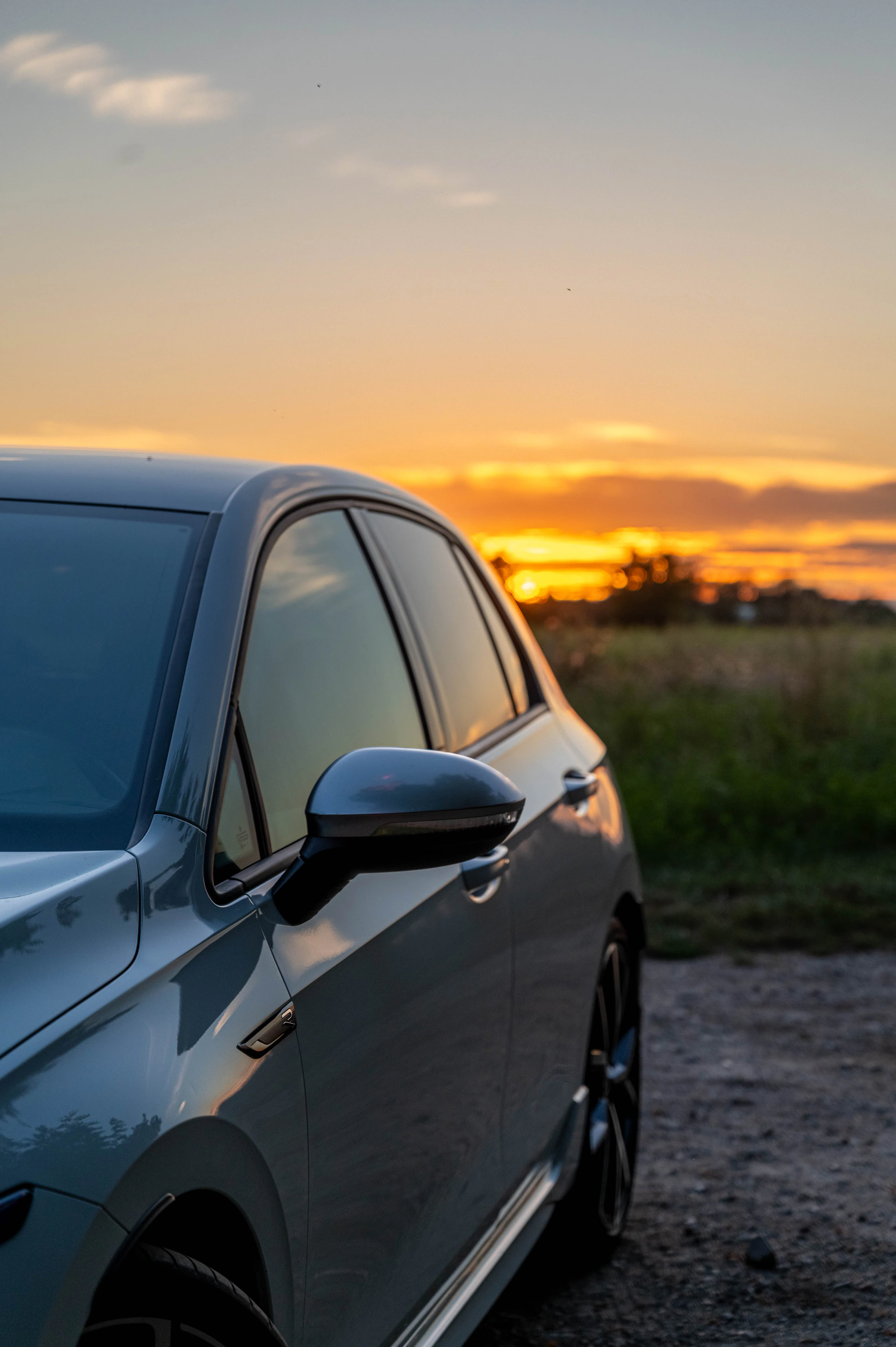 A car parked on a dirt road with a sunset in the background
