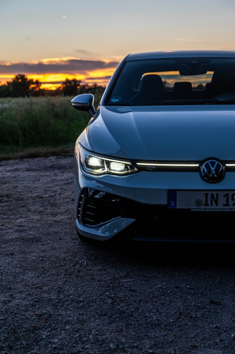 A car parked on a dirt road with the sun setting in the background