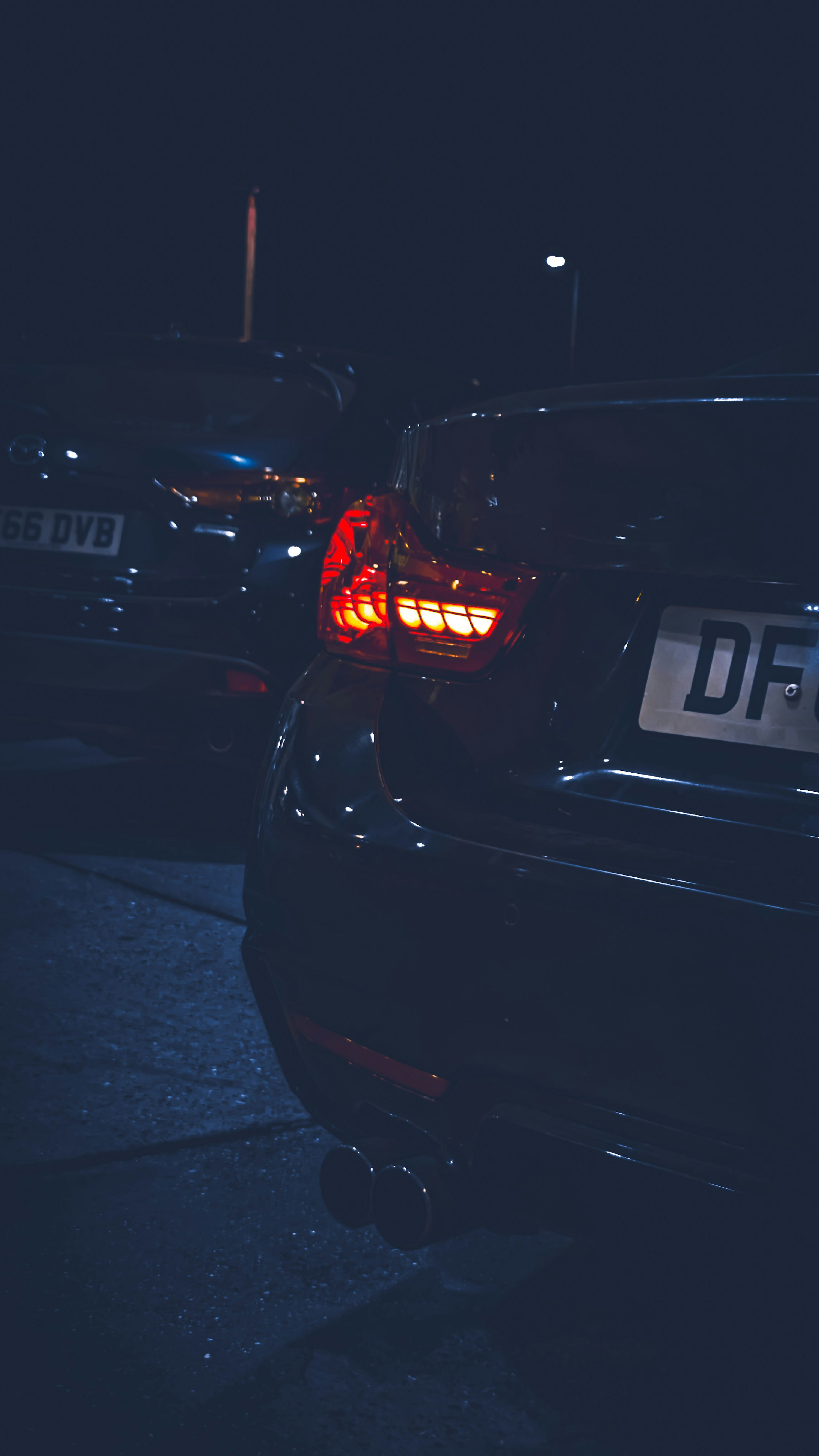 A row of parked cars in a parking lot at night
