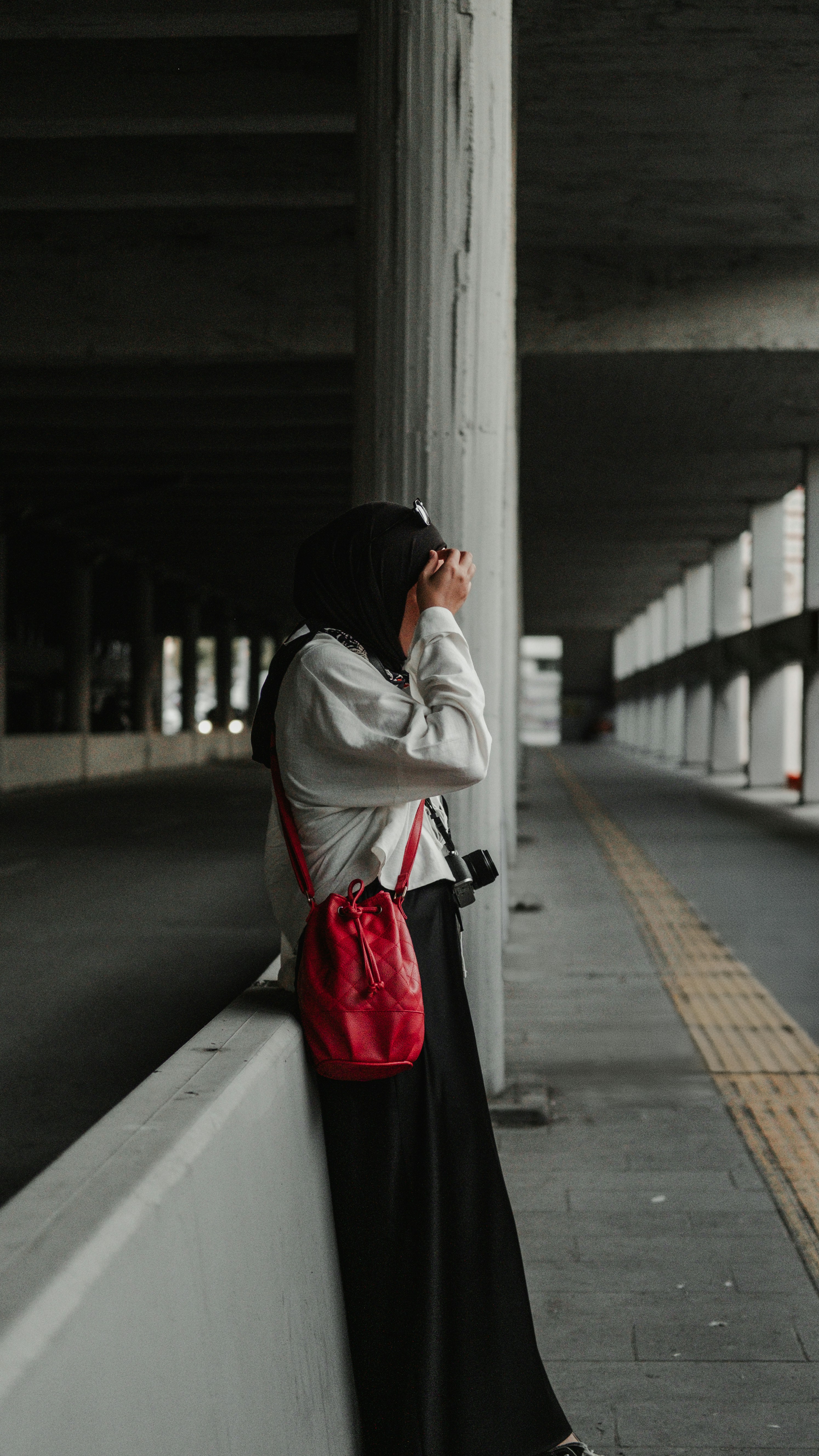 Una mujer apoyada en una pared hablando por teléfono celular