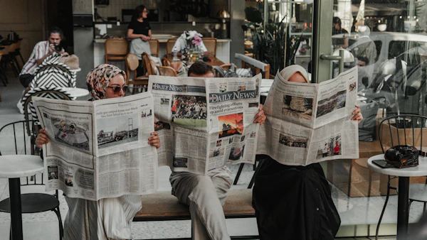 Hombre sentado en un banco leyendo un periódico