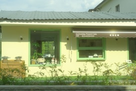 A yellow building with a green door and windows