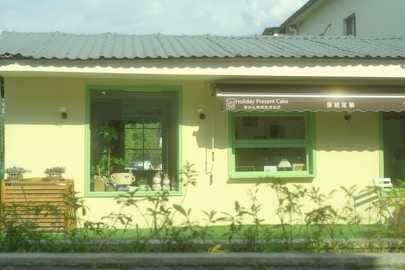 A yellow building with a green door and windows