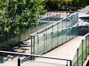 A tennis court with glass railings and trees