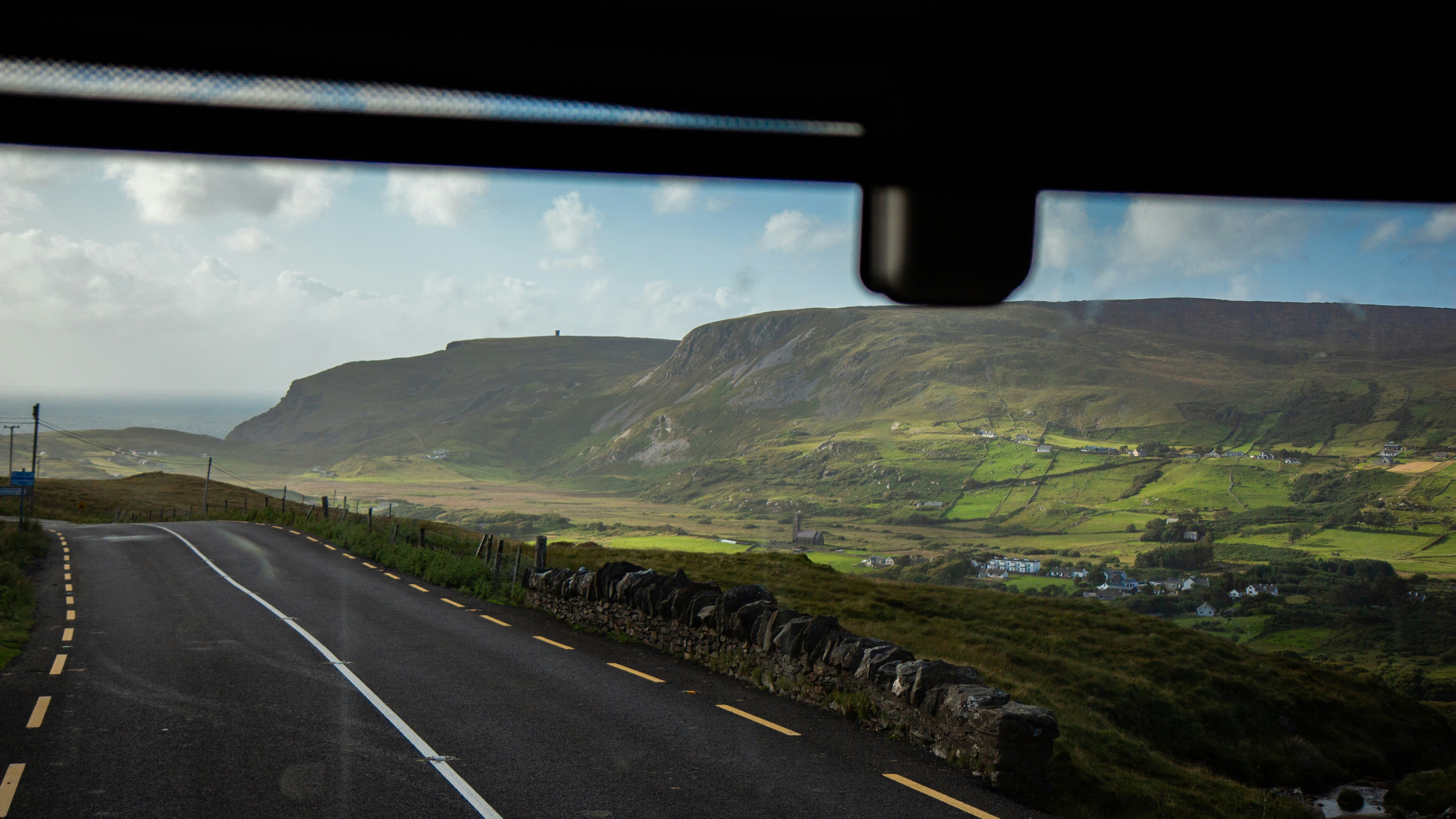 A view from inside a vehicle of a road with mountains in the background