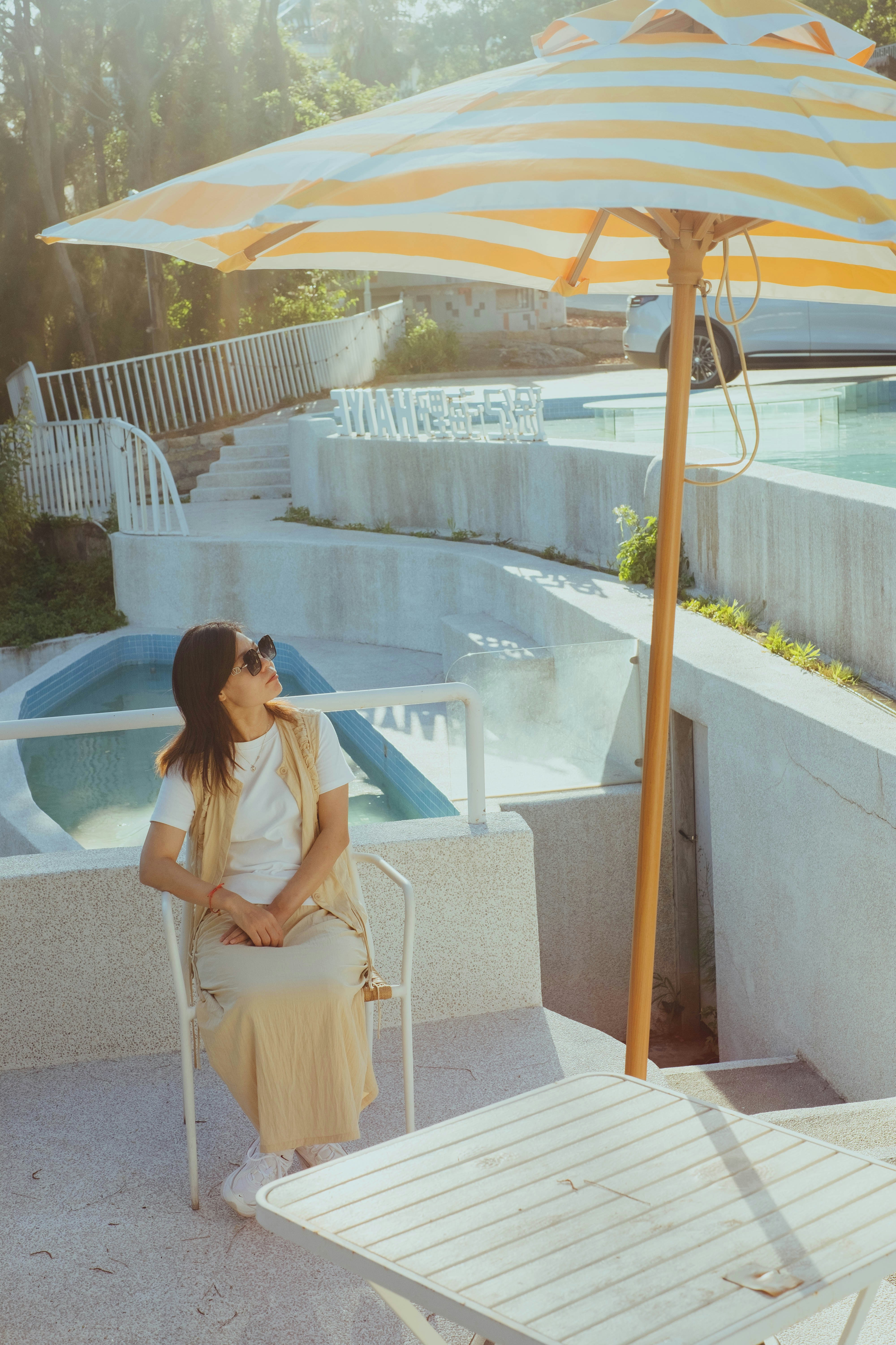 A woman sitting in a chair under an umbrella