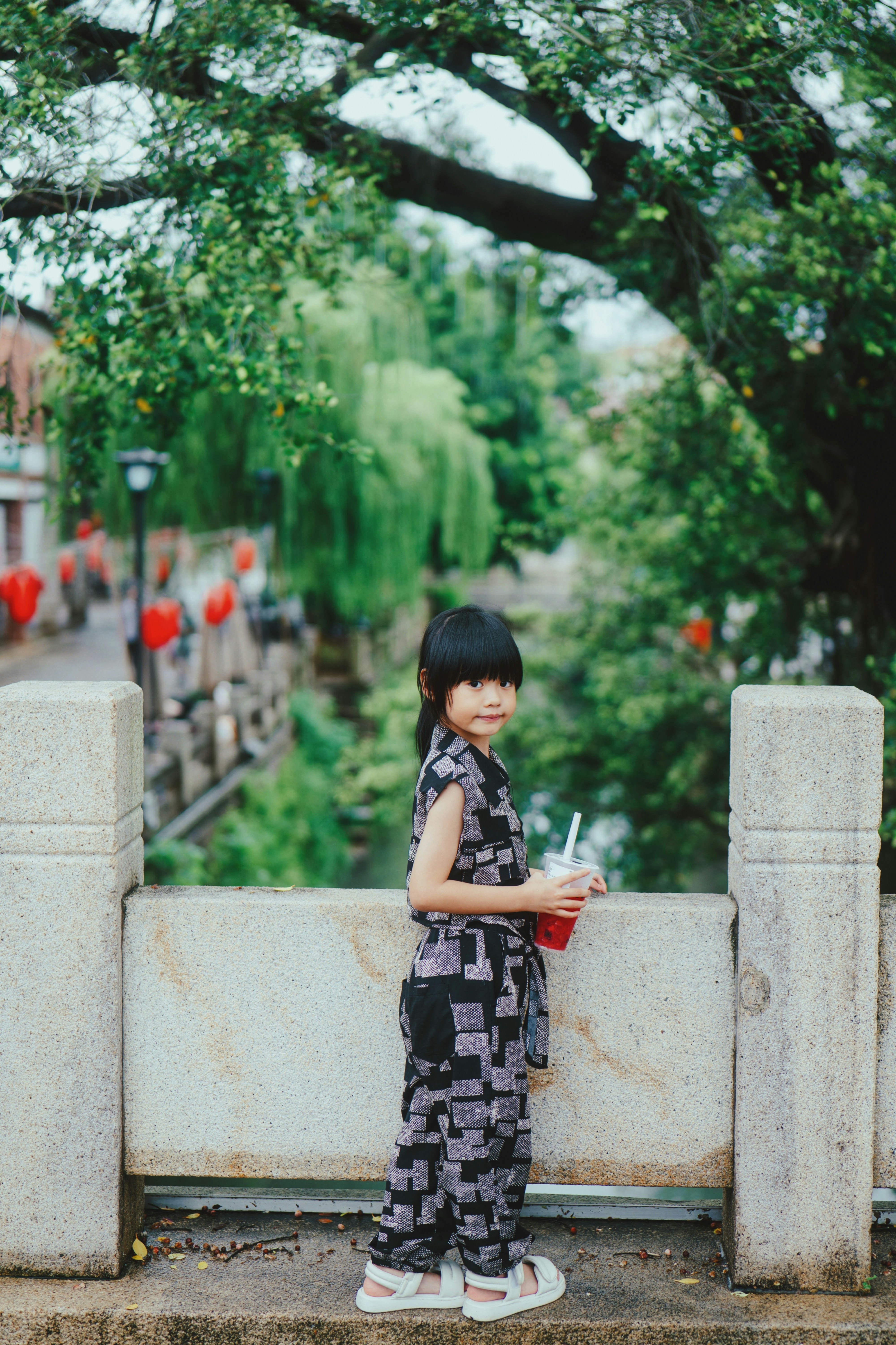 A little girl standing next to a cement wall