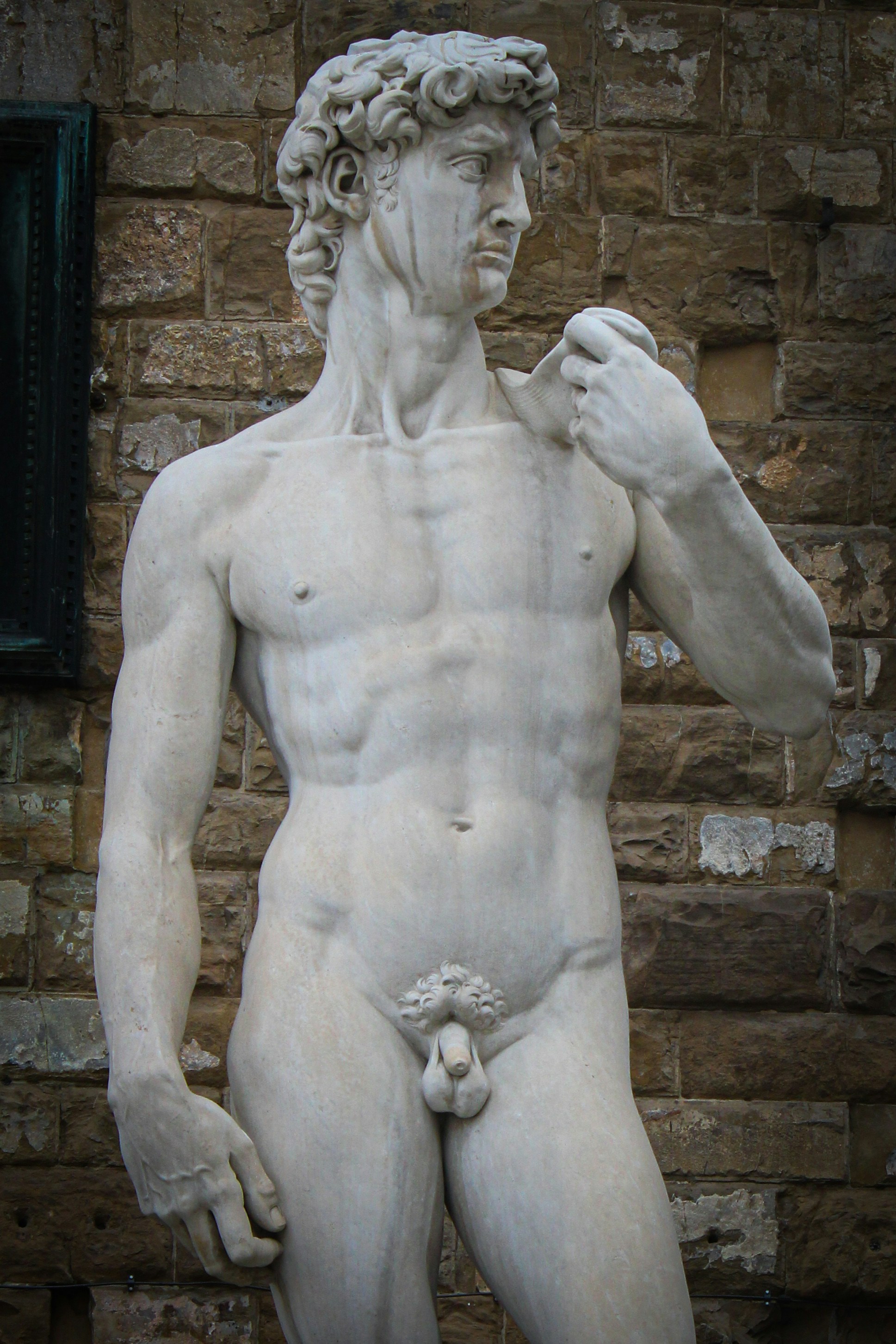 A statue of a man standing next to a brick wall