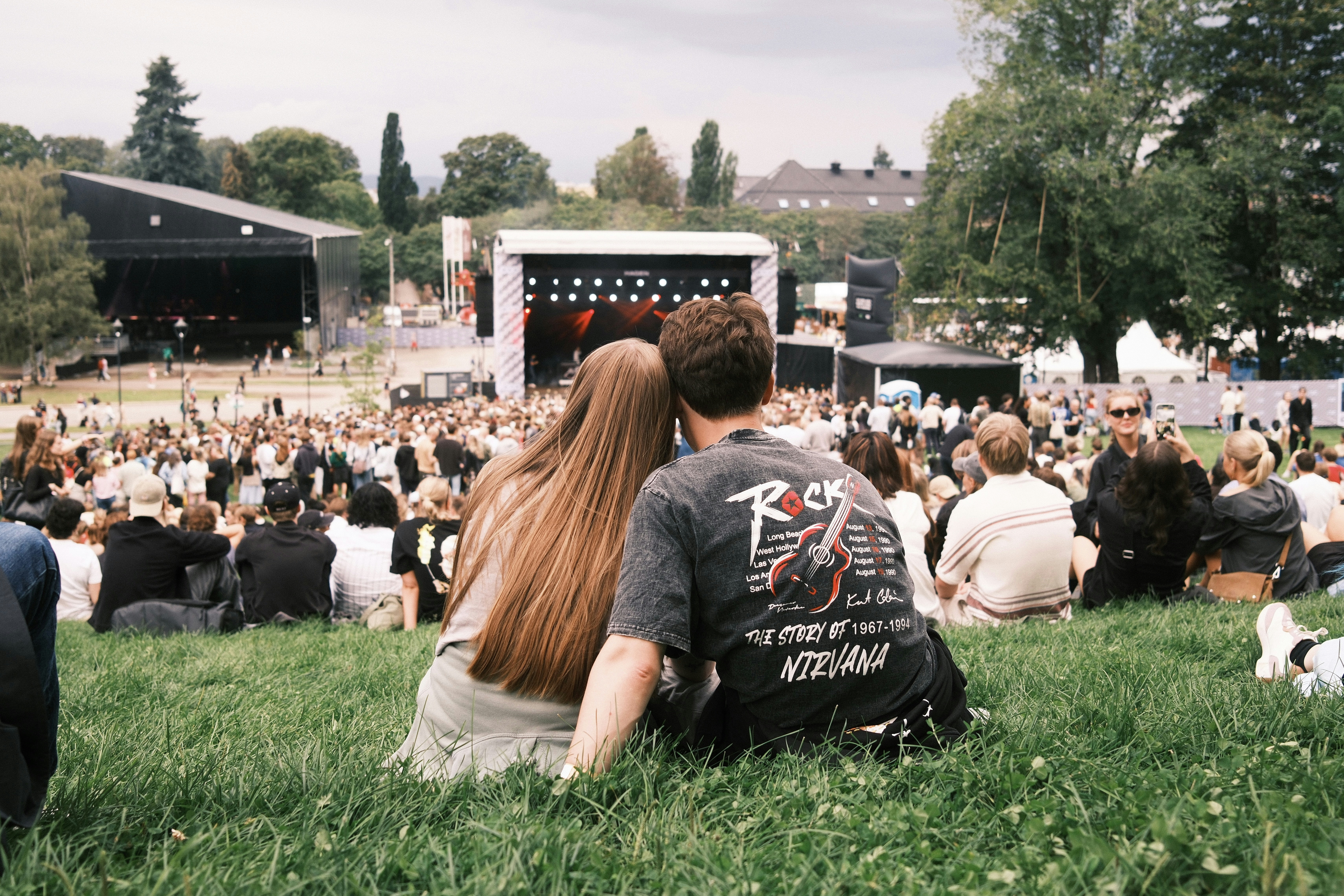 A man and a woman sitting on the grass watching a concert